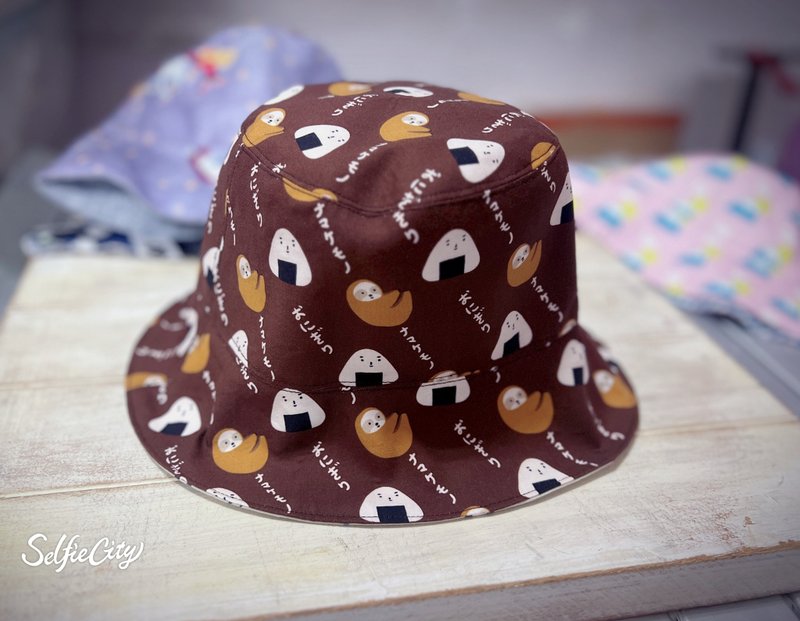 Brown Sloth Rice Ball Skunk Reversible Bucket Hat Sun Hat - หมวก - ผ้าฝ้าย/ผ้าลินิน สีนำ้ตาล