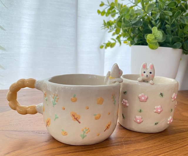 花模様とグラスにしがみついている猫が描かれた手作りの陶器製