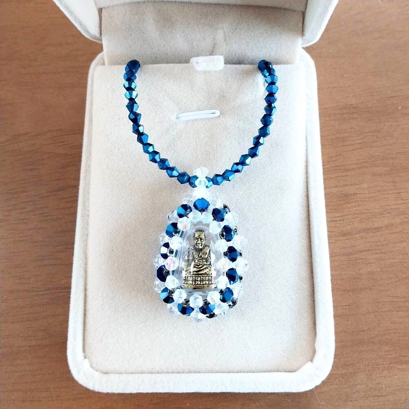 神聖なルアン プー トゥアット アミュレット ペンダントが付いたクリスタル ネックレス。ブルーのクリスタルに囲まれたフレームに。 - ネックレス - クリスタル 
